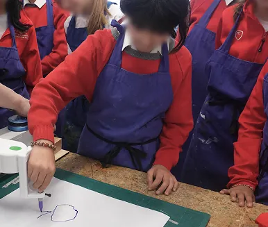 Students in aprons gathered around SwivelCut while one traces a shape with the tracing head