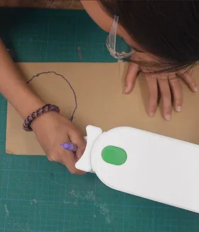 Overhead view of a student tracing a curved line on cardboard with the tracing head